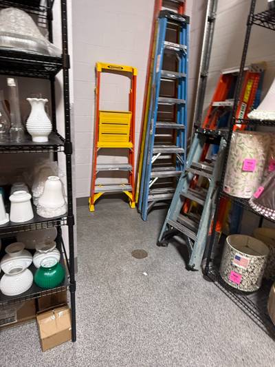 Multiple ladders leaning against wall in aisle