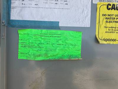 Green city inspection certificate taped on metal