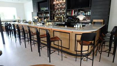 Bar area, L-shaped stone-top bar with leather barstools on carpet