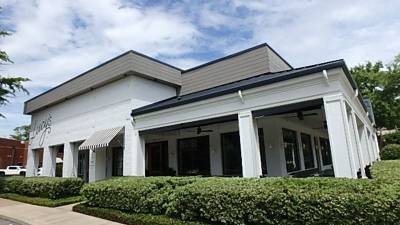 Covered wraparound patio with large windows and manicured perimeter hedges