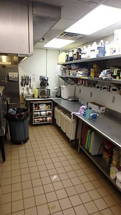 Prep area with stainless table, stand mixer, and chemical/dry-goods shelving